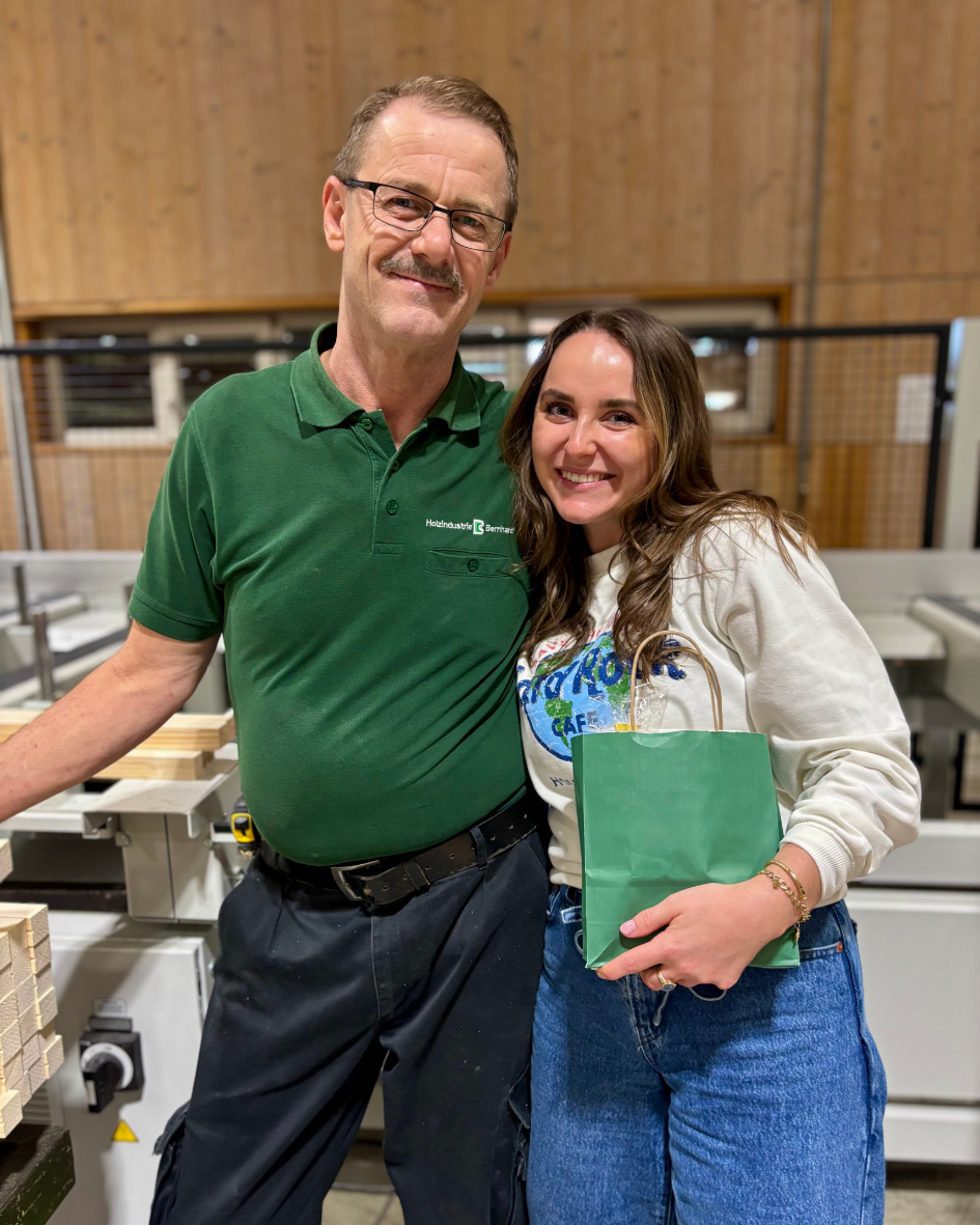 Mann steht an Maschine, Frau im Arm, Frau trägt Tüte