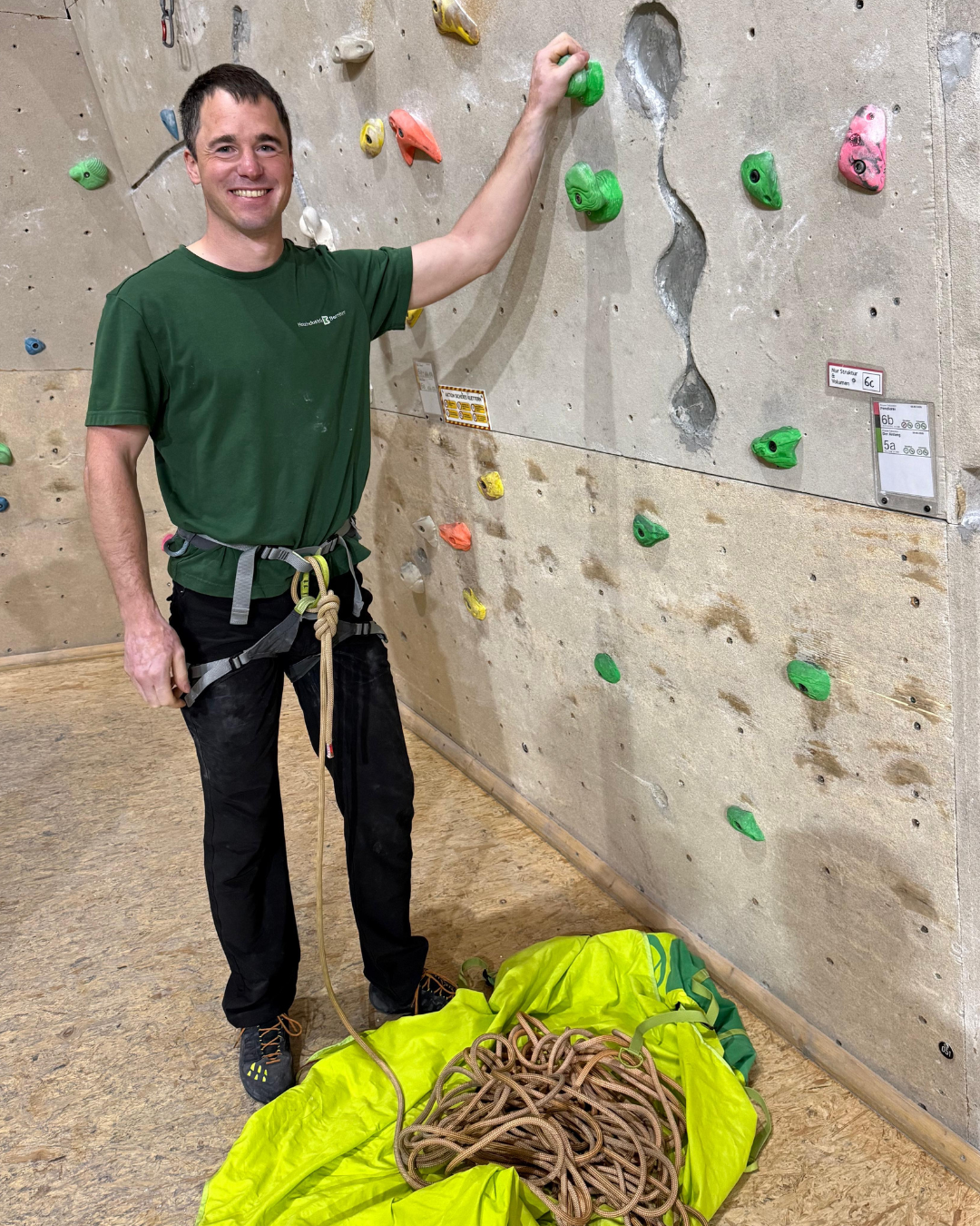 Wellpass - Mann steht in einer Kletterhalle an einer Boulderwand